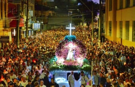 Multidão de homens carrega o andor de Nossa Senhora da Penha iluminado durante a programação Festa da Penha 2026.