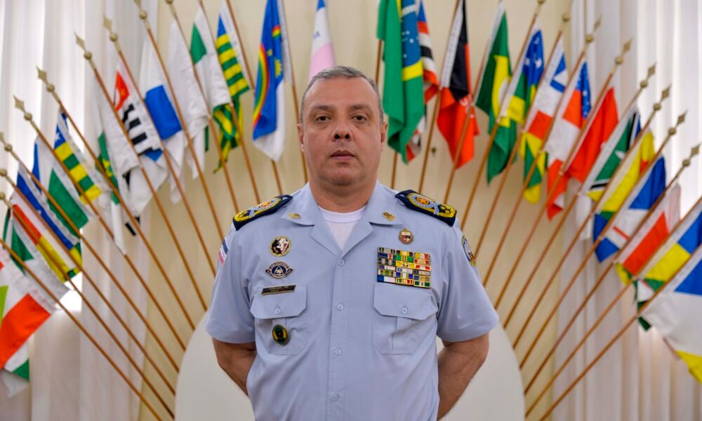 Coronel Douglas Caus em uniforme oficial diante de bandeiras no ES, ex-titular do comando da Polícia Militar do ES.
