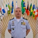 Coronel Douglas Caus em uniforme oficial diante de bandeiras no ES, ex-titular do comando da Polícia Militar do ES.
