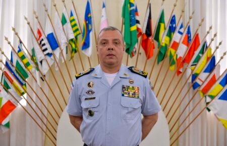 Coronel Douglas Caus em uniforme oficial diante de bandeiras no ES, ex-titular do comando da Polícia Militar do ES.