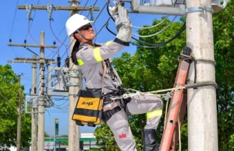 Fotografia de uma trainee em treinamento prático no Senai Serra conectando cabos elétricos, com sobreposição de texto em português: "Curso Gratuito de Eletricista. Bolsa de Estudo: R$ 900. Inscrições Abertas em Serra ES". Logotipos da EDP e Senai Serra visíveis.