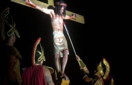 Ator na cruz e soldados romanos em cena noturna da encenação da Paixão de Cristo na Serra