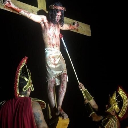 Ator na cruz e soldados romanos em cena noturna da encenação da Paixão de Cristo na Serra