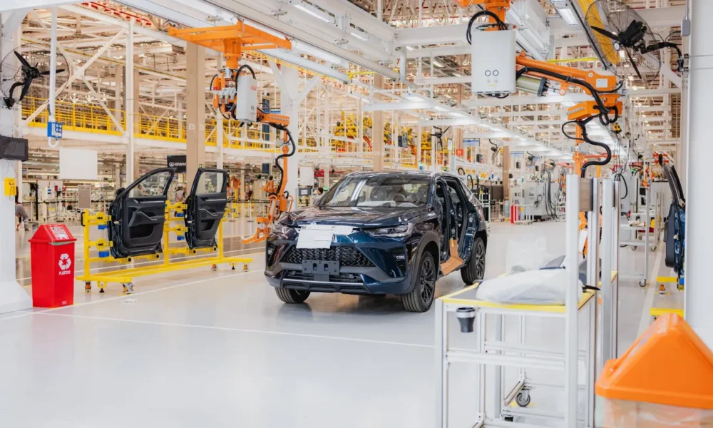 Linha de montagem com SUV azul e braços robóticos na futura fábrica da GWM no ES