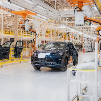 Linha de montagem com SUV azul e braços robóticos na futura fábrica da GWM no ES