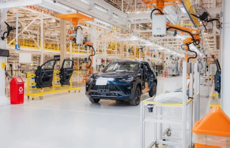 Linha de montagem com SUV azul e braços robóticos na futura fábrica da GWM no ES