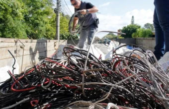 Agente de segurança pública manuseia grande quantidade de fiação de cobre e cabos de telecomunicações apreendidos após furtos de cabos na Serra.