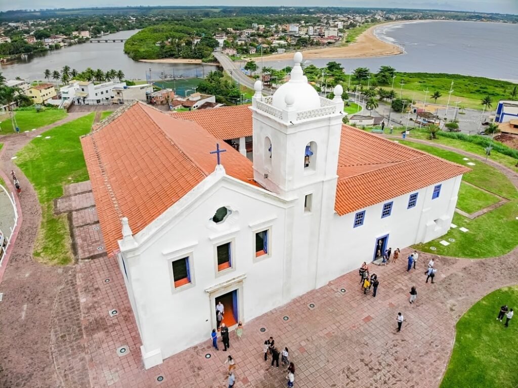 Vista aérea da Igreja dos Reis Magos em Nova Almeida, Serra, Espírito Santo, com o Rio Reis Magos e a praia ao fundo — patrimônio histórico tombado pelo IPHAN construído em 1580