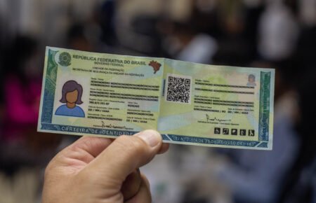 Mãos segurando o modelo da nova carteira de identidade ES que unifica documentos com QR code.