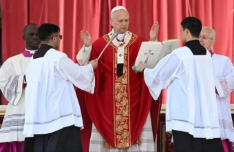 Papa Leão 14 com vestes vermelhas e mãos erguidas em oração durante missa de Papa Leão 14 Domingo de Ramos 2026 no Vaticano.