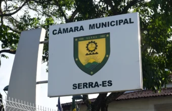 Placa branca com o brasão oficial e a identificação da Câmara Municipal da Serra, no Espírito Santo. A imagem ilustra as recentes medidas de modernização e o corte de gastos na Câmara da Serra promovidos pela atual gestão.