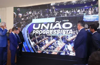 Políticos assistem ao anúncio da federação União Progressista em grande telão na Câmara dos Deputados.