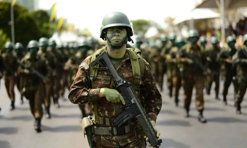 Soldado camuflado marchando com fuzil em desfile, imagem ilustrativa para as vagas do concurso Exército 2026