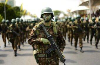 Soldado camuflado marchando com fuzil em desfile, imagem ilustrativa para as vagas do concurso Exército 2026