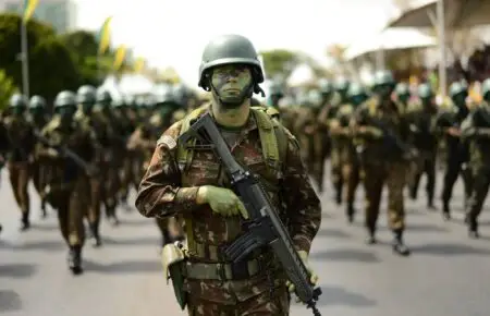 Soldado camuflado marchando com fuzil em desfile, imagem ilustrativa para as vagas do concurso Exército 2026
