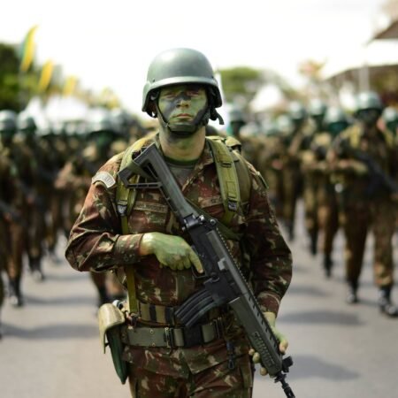Soldado camuflado marchando com fuzil em desfile, imagem ilustrativa para as vagas do concurso Exército 2026
