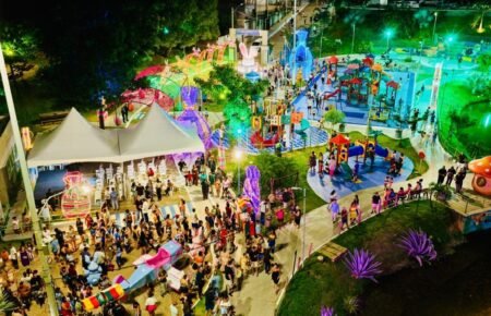 Vista aérea da Vila de Páscoa no Parque da Biquinha com coelho gigante iluminado e famílias circulando à noite