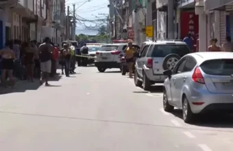Rua isolada com fita amarela pela polícia após caso de violencia Terra Vermelha Vila Velha, com viatura estacionada no centro da via e diversos moradores observando a cena do crime nas calçadas.