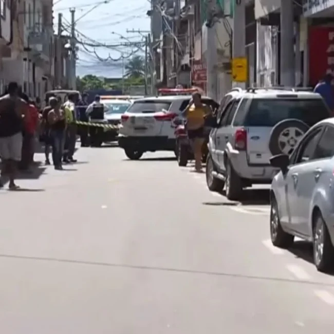 Rua isolada com fita amarela pela polícia após caso de violencia Terra Vermelha Vila Velha, com viatura estacionada no centro da via e diversos moradores observando a cena do crime nas calçadas.